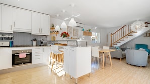 Une cuisine moderne avec des meubles blancs, un îlot central et des luminaires suspendus.