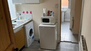 Uma cozinha compacta com máquina de lavar, micro-ondas e pia.