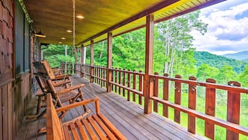 Une terrasse en bois avec des bancs donnant sur un paysage boisé.