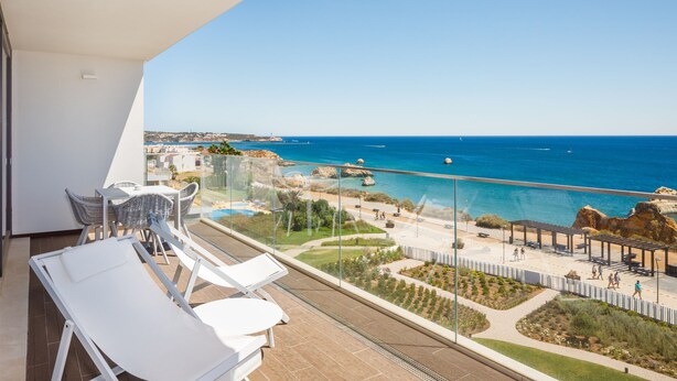 Un balcon avec vue sur la mer, une piscine et un jardin.