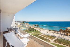 Un balcón con vista al mar, una piscina y un jardín.