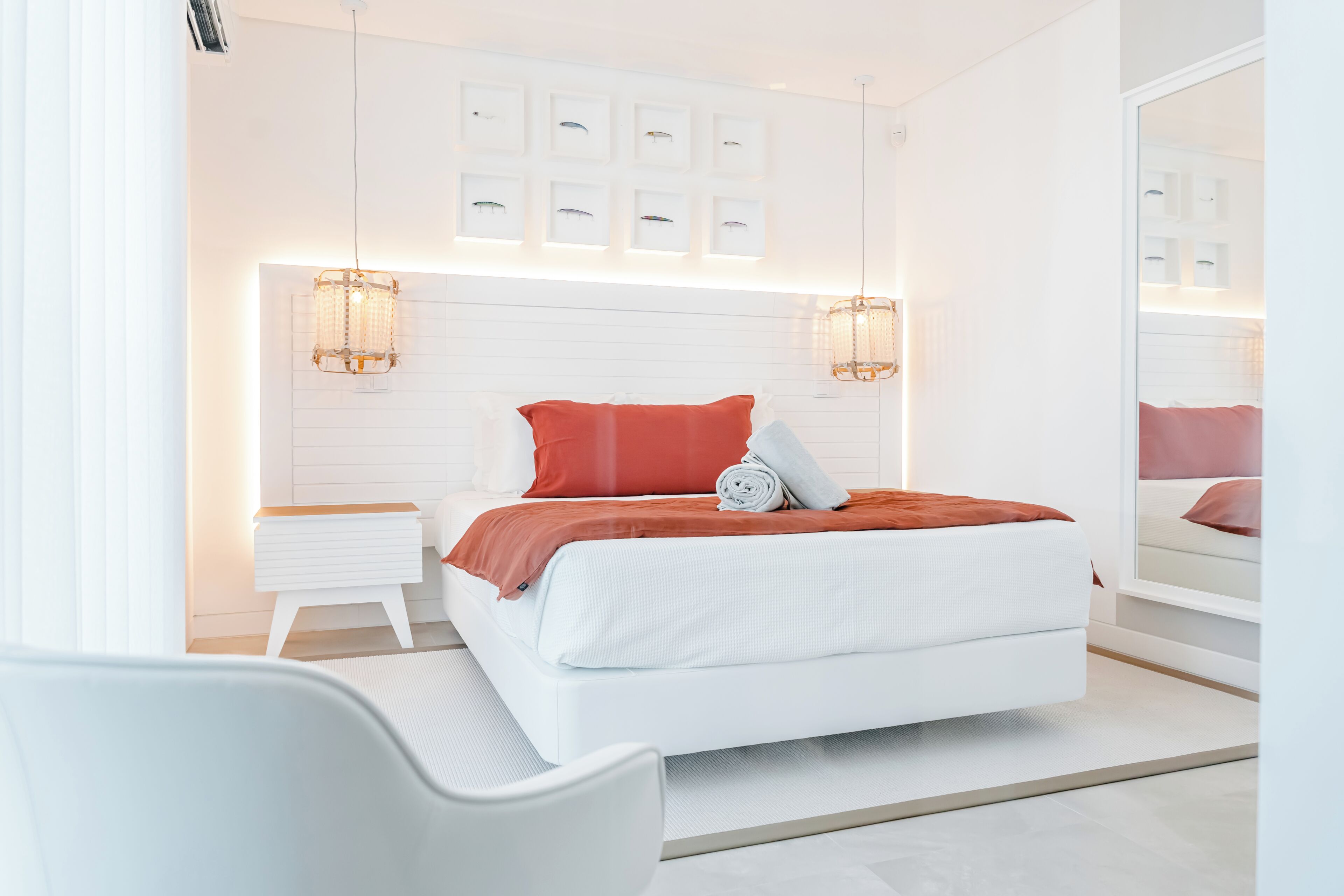 A modern bedroom with a bed, bedside tables, a chair, and a large mirror.