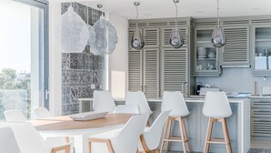 Une cuisine moderne avec des meubles blancs, un îlot central en bois et des luminaires suspendus.