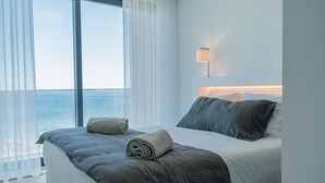Une chambre d’hôtel moderne avec un grand lit, une vue sur la mer et une lampe de chevet.