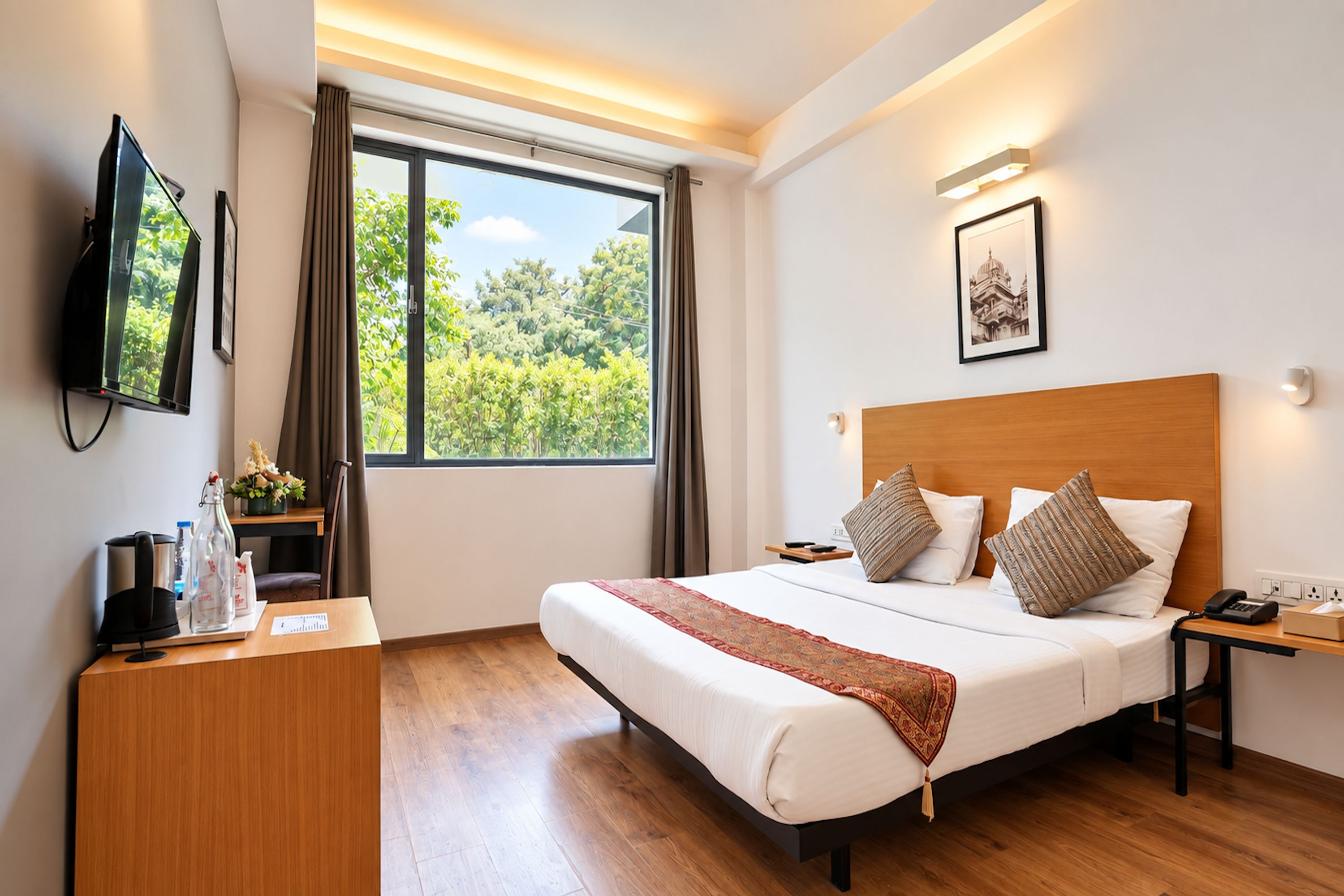 A hotel room with a bed, bedside table, lamp, TV, and a window with a view of greenery.