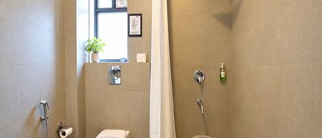 Un baño con inodoro, ducha y una pequeña ventana con una planta.