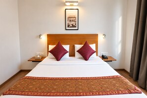 A hotel room with a large bed, two bedside tables, a telephone, and a framed picture on the wall.