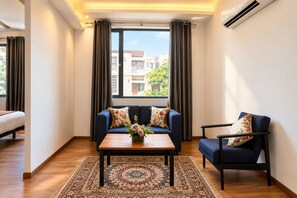 Una habitación de hotel moderna con sofá, sillón y una mesa de centro con un centro de flores.