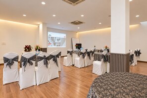A conference room with white chairs, a projector screen, and a wooden floor. - Enkay Residency Sector 15 (Gurugram)