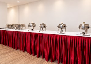 A conference room with a long table covered by a red tablecloth, equipped with several buffet stations. - Enkay Residency Sector 15 (Gurugram)