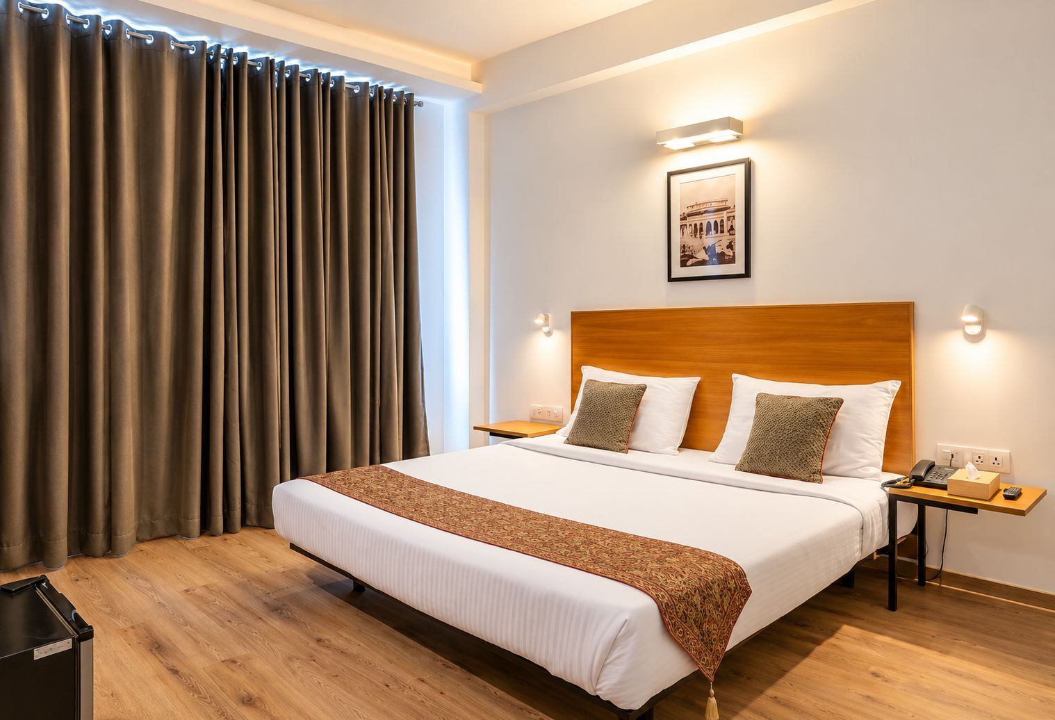 A hotel room with a large bed, two bedside tables, a headboard, and a wall-mounted picture.
