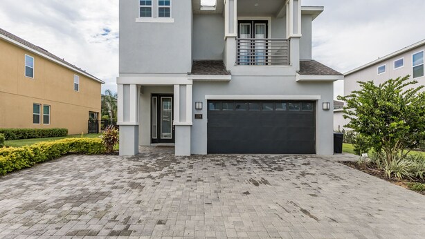 Um edifício residencial de dois andares com garagem, varanda e entrada para carros.