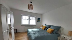 Una camera da letto con un letto, comodini, una finestra, un termosifone e un armadio.