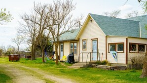 A single-story house with a green roof, a front porch, and a small front yard. - Cozy private Lakehouse with prime fishing, hunting, and lake access. (Webber)