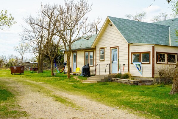 A single-story house with a green roof, a front porch, and a small front yard.