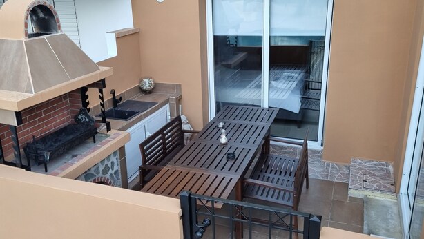 A balcony with a brick oven, a table with chairs, and a view of the interior. - 2br-7 Guests-free Parking-pool-aircon (Paralimni)