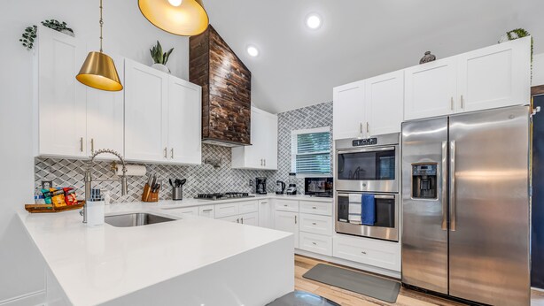 A modern kitchen with white cabinets, stainless steel appliances, and a central island.