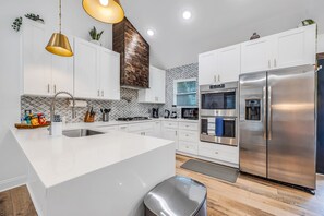 A modern kitchen with white cabinets, stainless steel appliances, and a central island. - Harmony House, Sleeps 8 (Decatur)