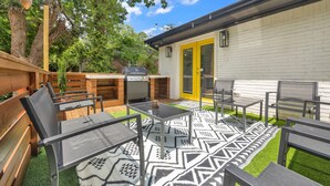 An outdoor patio with a barbecue area, seating, and a patterned rug.