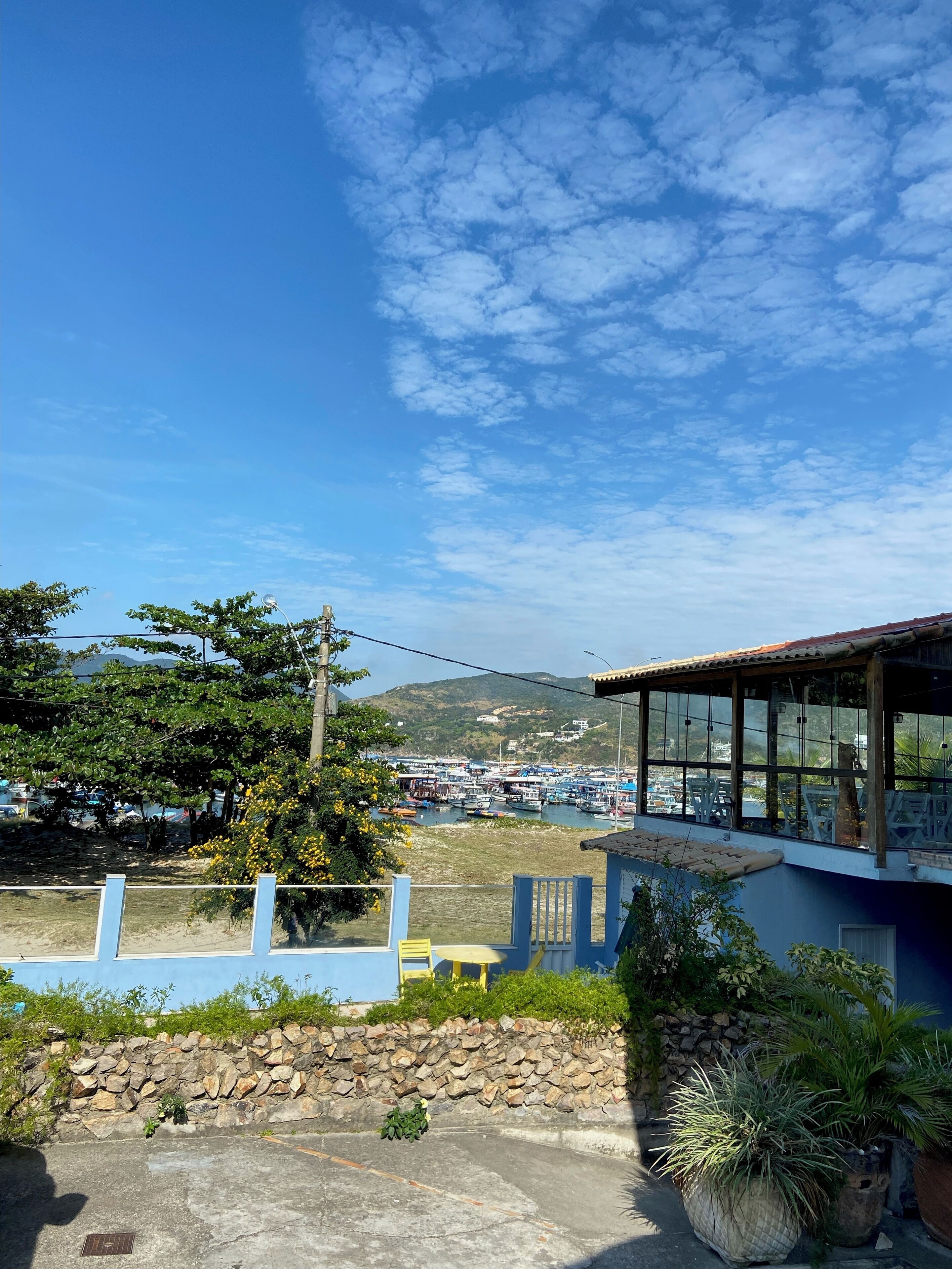 A coastal view with a marina, a stone wall, and a building with large windows.