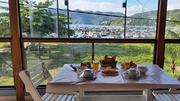 Une table dressée pour le petit-déjeuner, avec vue sur une marina et des collines.