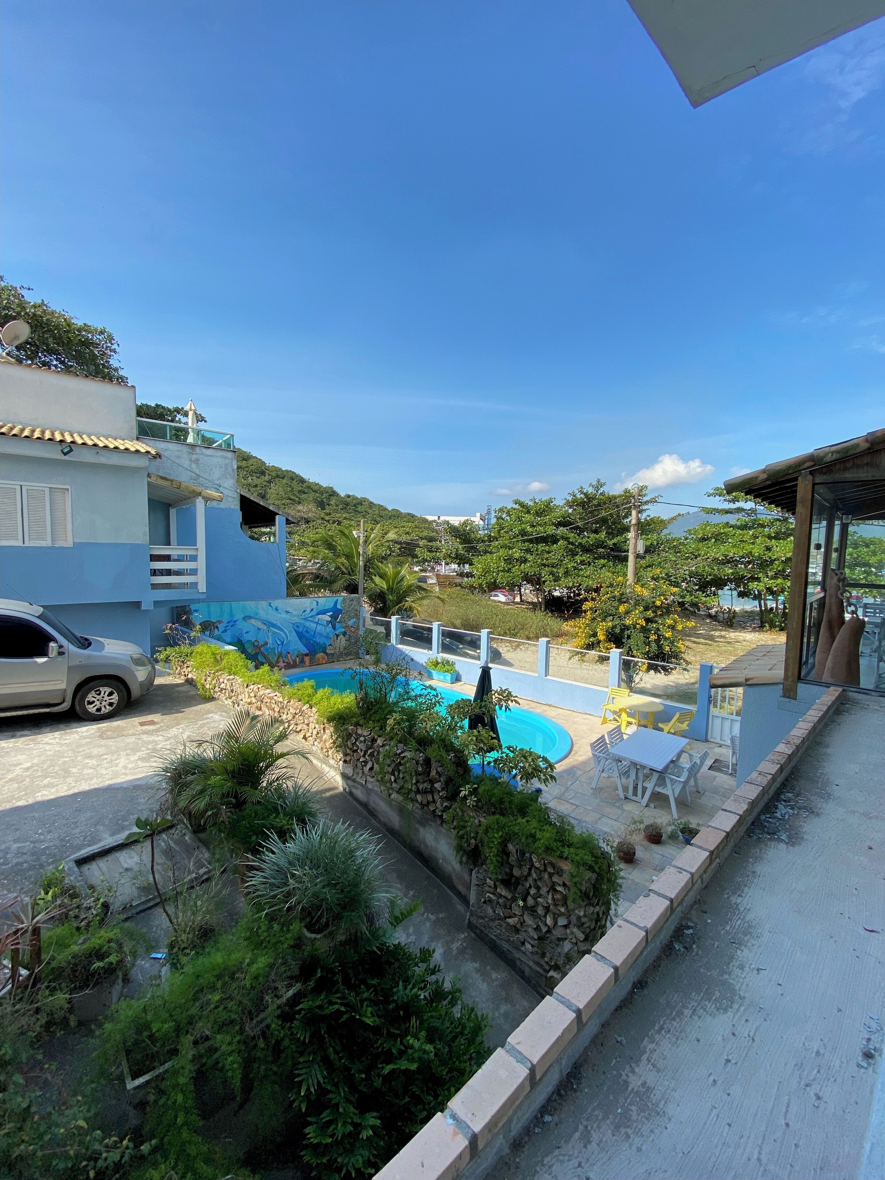 A residential property with a swimming pool, outdoor seating, and a view of a hilly landscape.