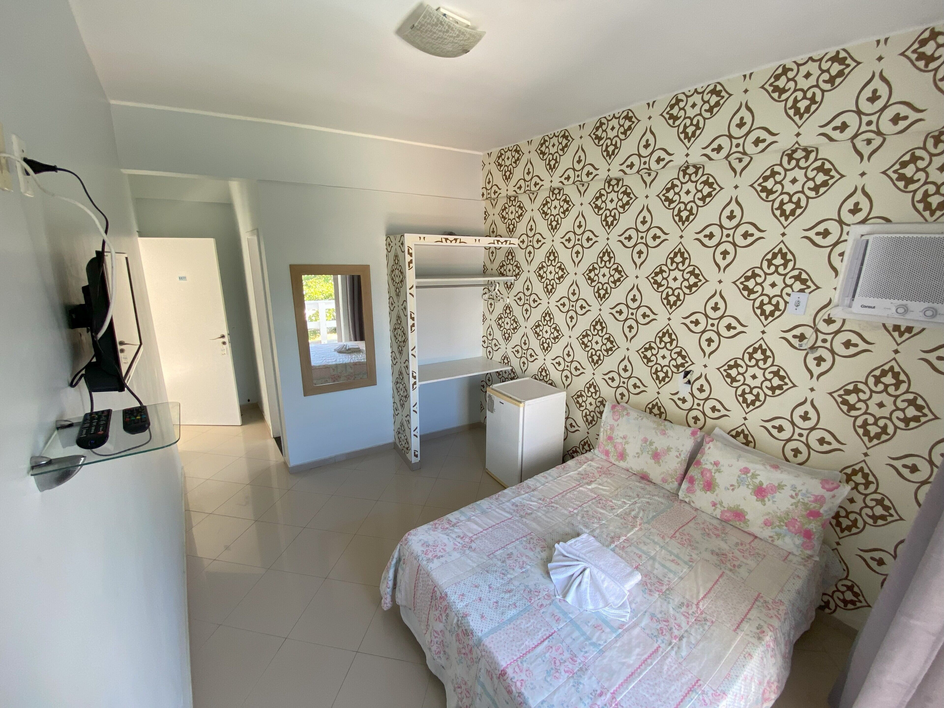 A bedroom with a bed, a bedside table, a wardrobe, a mirror, and a ceiling fan.