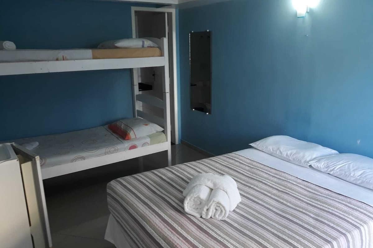 Ein Zimmer mit Etagenbetten, einem Schreibtisch und einem Bett mit gestreifter Bettdecke und einem zusammengerollten Handtuch.