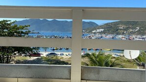Un balcon offrant une vue dégagée sur un port de plaisance, des bateaux et des montagnes lointaines.