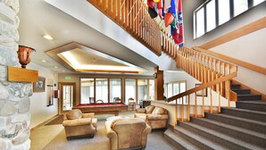 Eine geräumige Lobby mit Billardtisch, Ledersofas und einer Holztreppe.