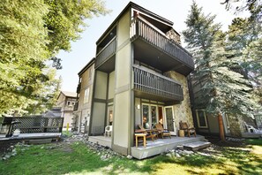Ein zweistöckiges Haus mit Balkon, Sitzgelegenheit im Freien und einer Stein-Fassade.