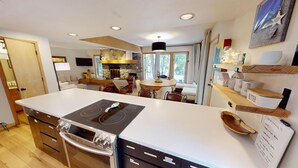 Eine moderne Küche mit einer großen Kochinsel, einem eingebauten Backofen und einem Essbereich mit rundem Tisch und Stühlen.