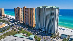 A high-rise hotel with multiple floors, a beach view, and a parking area.