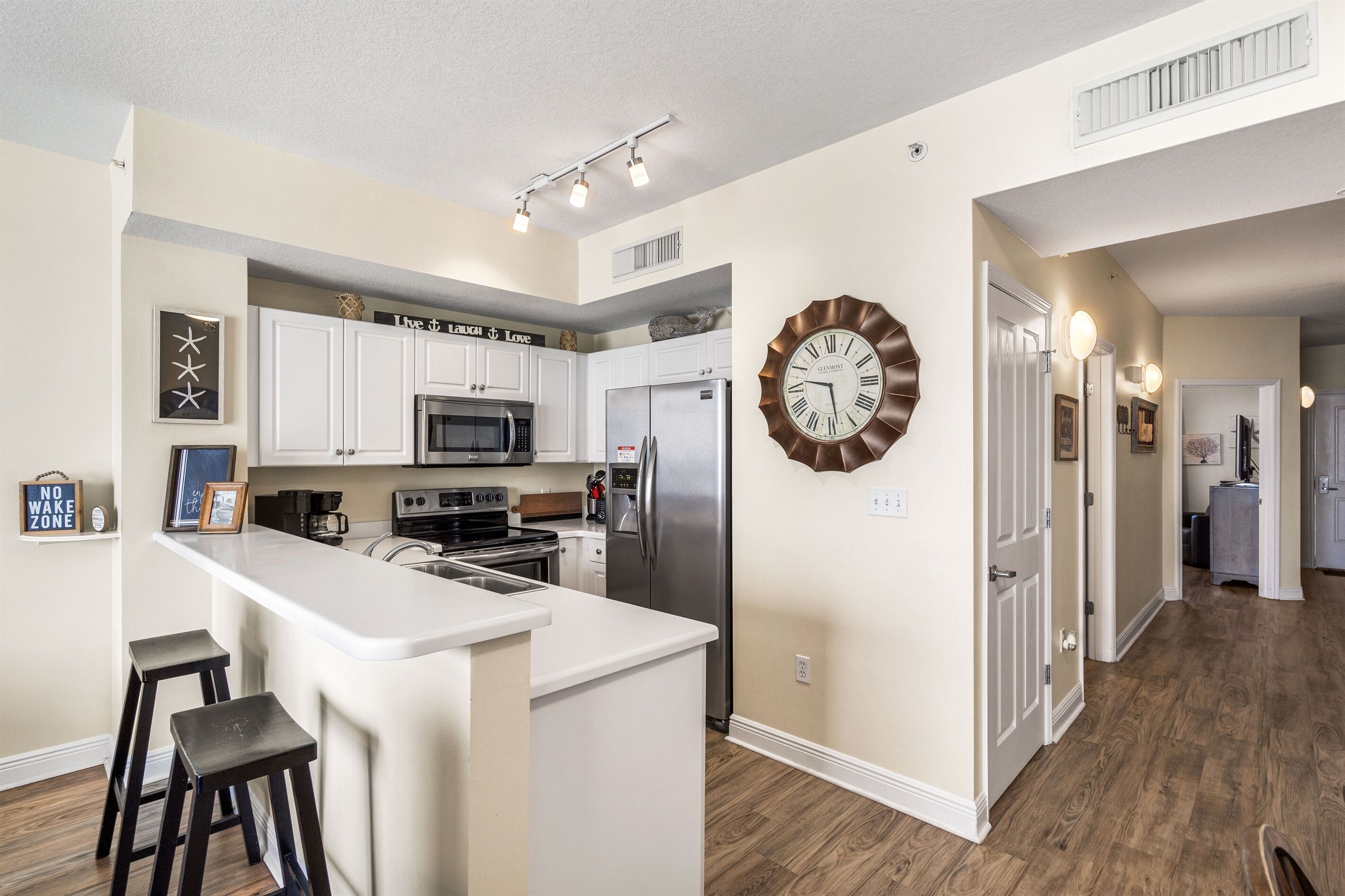 A modern kitchen with white cabinets, stainless steel appliances, and a central island with stools.