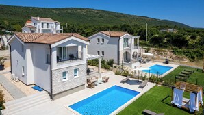Ein Wohnhaus mit Swimmingpool, Sitzgelegenheiten im Freien und Blick auf die umliegenden Hügel.