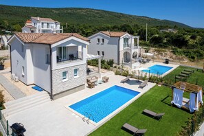 Una propietat residencial amb piscina, zona de seients a l'exterior i vistes als turons circumdants.