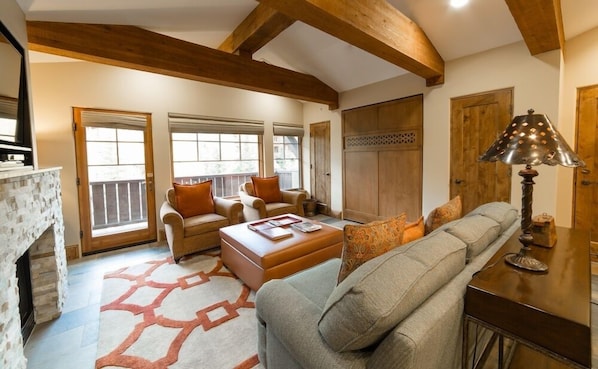 A spacious living room with a fireplace, wooden beams, a sofa, a coffee table, and a lamp.