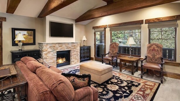 A cozy living room with a fireplace, wooden beams, comfortable seating, and large windows. - Two Bedroom Suite 2 Apartment Hotel by RedAwning (Park City)