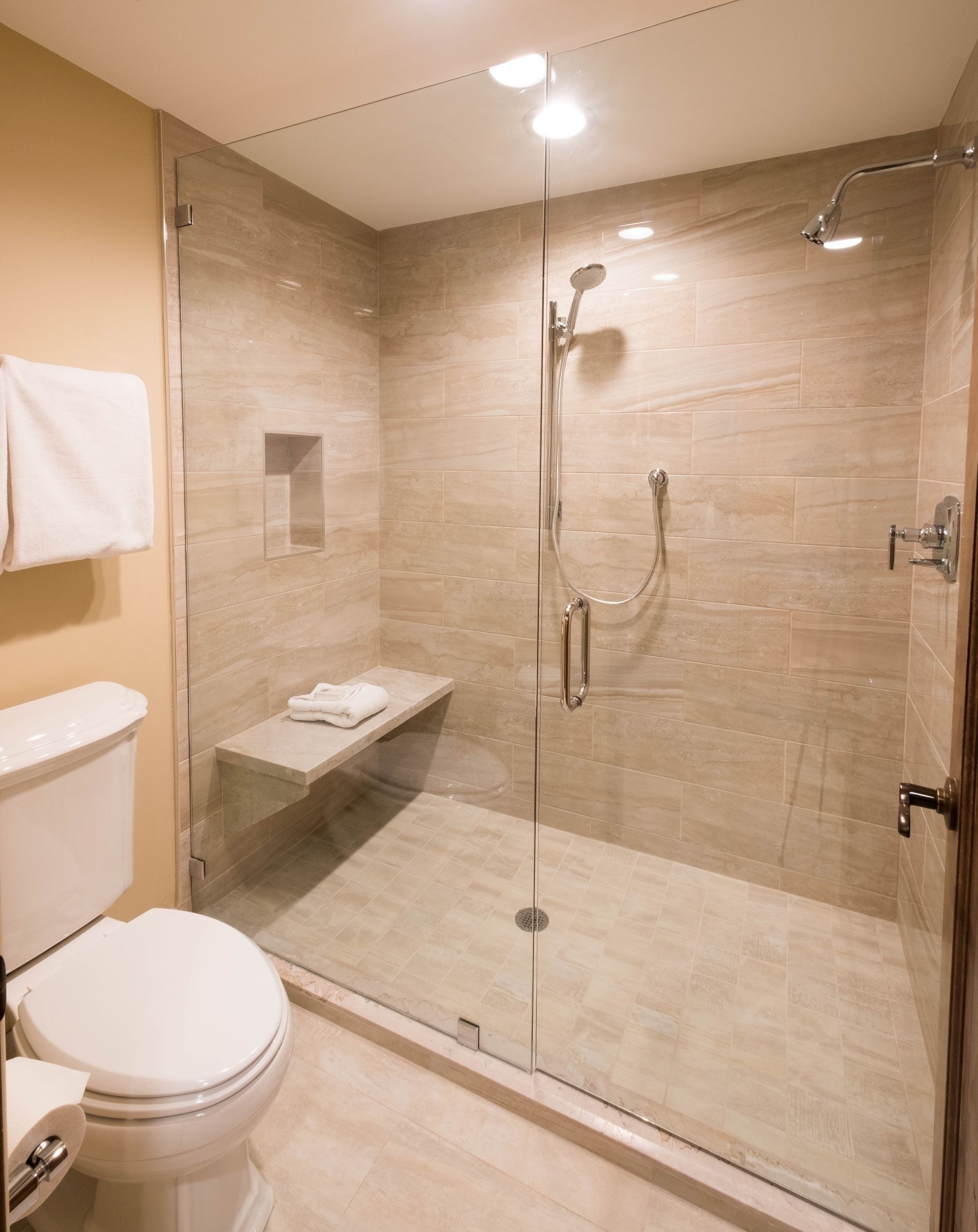 Un baño moderno con ducha de vidrio, inodoro y perchero para toallas.