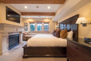 A bedroom with a large bed, a fireplace, a TV mounted on the wall, and a window with a view of trees. - Three Bedroom Suite 3 Apartment Hotel by Redawning (Park City)