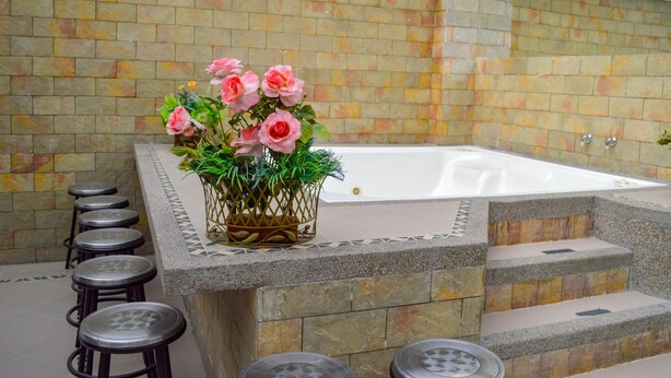 A spa area with a bathtub, stone steps, and a flower arrangement. - Hotel Andinos Plaza (Pitalito)