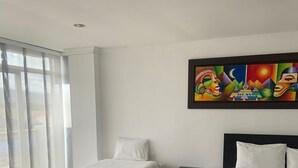 A hotel room with two beds, a nightstand, and a colorful abstract painting on the wall. - Hotel Andinos Plaza (Pitalito)