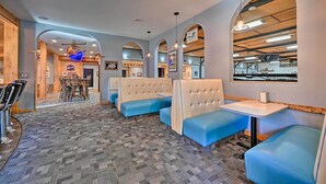 Un restaurante con asientos tipo banca en azul, una zona de bar y una alfombra estampada.