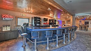 Zona de bar con un letrero de neón, taburetes, una barra y techo de madera.