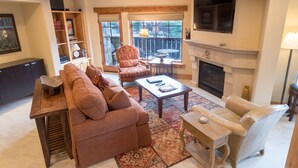 A living room with a fireplace, a sofa, a chair, a coffee table, and a bookshelf.