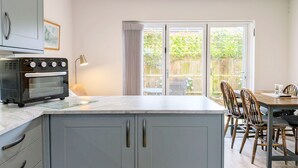 A kitchen with a built-in oven, a dining area with a table and chairs, and a sliding glass door leading to a backyard. - Pears Grove - Southbourne - a family house that sleeps 6 guests in 3 bedrooms (Emsworth)
