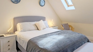 A bedroom with a bed, bedside tables, a nightstand, a chair, and a skylight. - Pears Grove - Southbourne - a family house that sleeps 6 guests in 3 bedrooms (Emsworth)