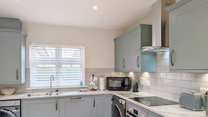 A modern kitchen with grey cabinets, a built-in microwave, a dishwasher, and a sink. - Pears Grove - Southbourne - a family house that sleeps 6 guests in 3 bedrooms (Emsworth)