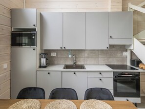A modern kitchen with grey cabinets, a Bosch microwave, a sink, and a dining area with a table and chairs.