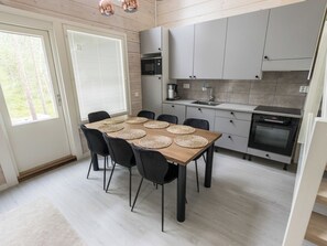 Une cuisine moderne avec une table à manger pour six personnes, équipée d’une machine à café et d’un four encastré.
